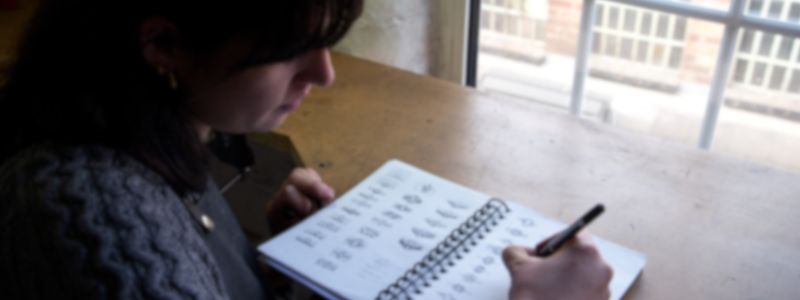 A lady writing in on her notepad. This is sits on the page that helps people create an invoice.
