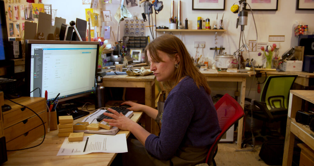 Small Business Owner sitting at desk working on a computer. This image sits on the e-invoicing for small businesses page.